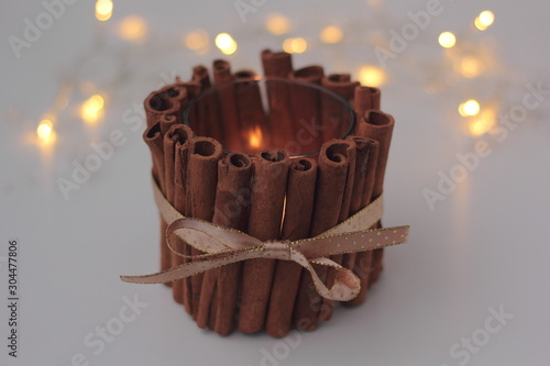Obraz na płótnie Closeup of DIY cinnamon candle holder with burning candle on white background. Concept of Christmas DIY and zero waste, sustainable decoration. w salonie