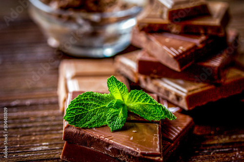 chopped chocolate pieces with mint for dessert wooden desk background
