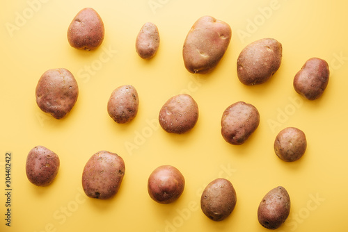 top view of raw whole fresh potatoes on yellow background