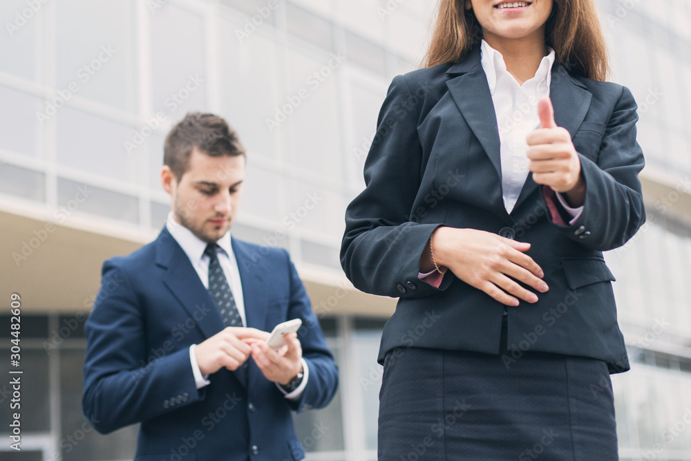 Successful young business woman showing thumbs up sign standing in front of his office. Successful young business woman showing thumbs up sign standing in front of his office.