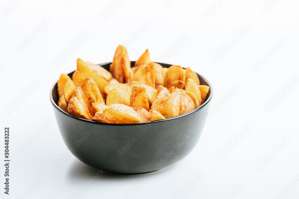 delicious golden potato wedges in bowl on white background delicious golden potato wedges in bowl on white background