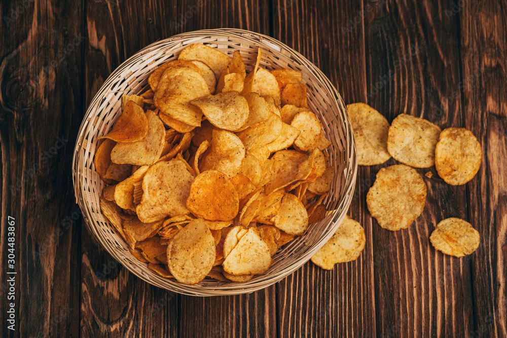 Foto Stock top view of delicious crispy potato chips in wicker basket on  wooden table | Adobe Stock