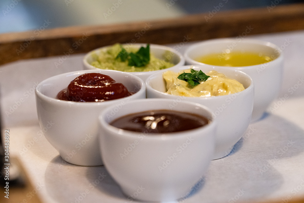 Small bowls with different sauces on a tray in a restaurant Small bowls with different sauces on a tray in a restaurant