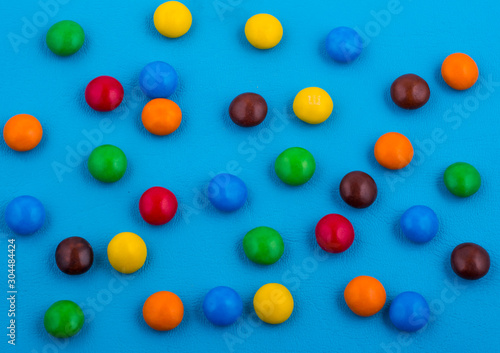 bright background made of colored chocolate candy on a blue background