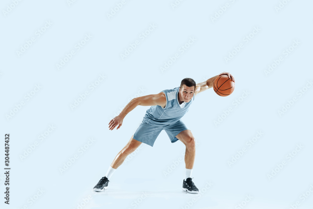 Champion. Young caucasian basketball player of team in action, motion in jump isolated on blue background. Concept of sport, movement, energy and dynamic, healthy lifestyle. Training, practicing.