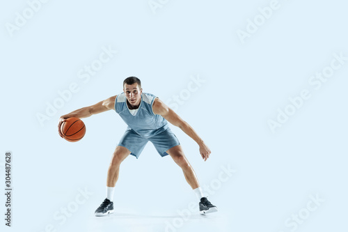 Champion. Young caucasian basketball player of team in action, motion in jump isolated on blue background. Concept of sport, movement, energy and dynamic, healthy lifestyle. Training, practicing. © master1305