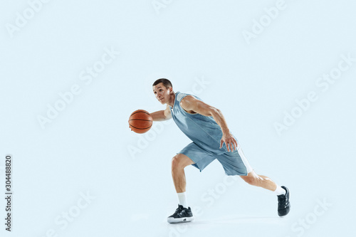 Champion. Young caucasian basketball player of team in action, motion in jump isolated on blue background. Concept of sport, movement, energy and dynamic, healthy lifestyle. Training, practicing.