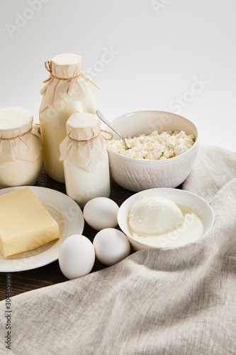 delicious fresh dairy products and eggs on wooden table with cloth isolated on white