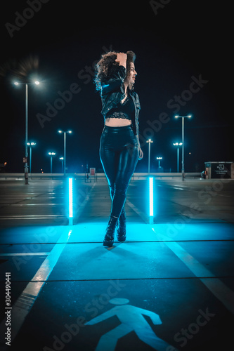 Past of a young woman in an urban night session with blue lights