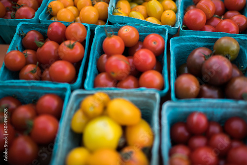 Pint baskets of organic red tomatoes on the counter. Fresh organic produce on sale at the local farmers market. Organic, agriculture products. Freshly, seasonal harvested vegetables. Bio, healthy.