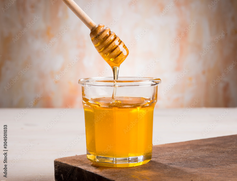 Honey and dipper in glass jar on a wooden floor Honey and dipper in glass jar on a wooden floor