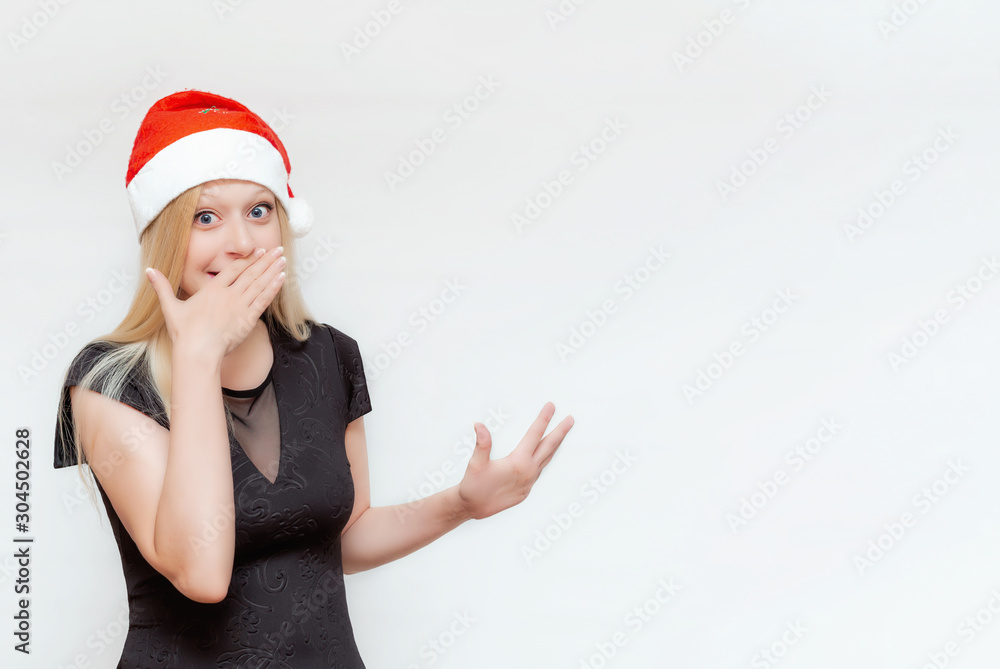 Emotional portrait of a beautiful girl making hand gestures in a Christmas hat on a white background. Space for text. Empty space. Flat lay Emotional portrait of a beautiful girl making hand gestures in a Christmas hat on a white background. Space for text. Empty space. Flat lay