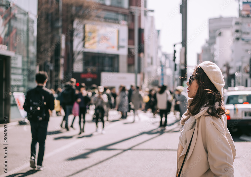 Asian girl standing out from the crowd at a city street in Japan.