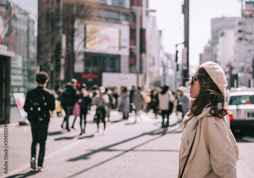 Asian girl standing out from the crowd at a city street in Japan. © grooveriderz