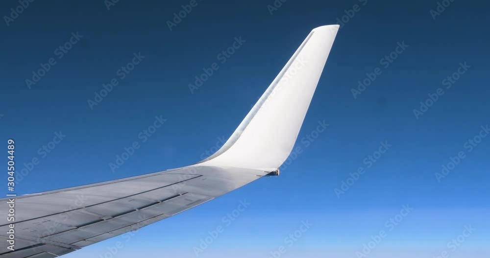 Plane is flying against of a clean blue sky background. View white wing through an airplane window. Hand shot filmed in 4k UHD 2160p Plane is flying against of a clean blue sky background. View white wing through an airplane window. Hand shot filmed in 4k UHD 2160p