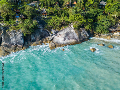 Aerial view of turquoise waves beating on stones. Thailand