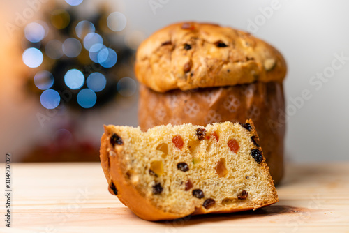 Delicious Panettone slice with candied fruits with blinking blurred christmas lights. Dry fruits. photo