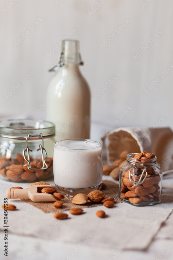 Fresh organic vegan almond milk. Alternative source of protein for vegetarians. Raw almonds, peeled and unpeeled to illustrate ingredients. Concept of healthy lifestyle. Closeup, white background Fresh organic vegan almond milk. Alternative source of protein for vegetarians. Raw almonds, peeled and unpeeled to illustrate ingredients. Concept of healthy lifestyle. Closeup, white background
