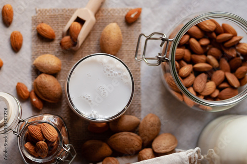 Fresh organic vegan almond milk. Alternative source of protein for vegetarians. Raw almonds, peeled and unpeeled to illustrate ingredients. Concept of healthy lifestyle. Closeup, top view, background