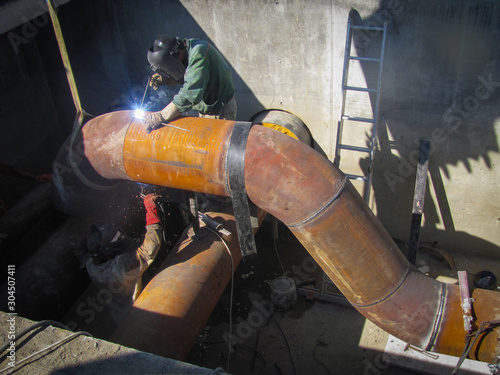 Welders weld large metal pipes in trenches at actual plant construction, laying pipes, pouring foundation, knitting fittings, debris, autumn, trench, Rusted gas and oil pipeline