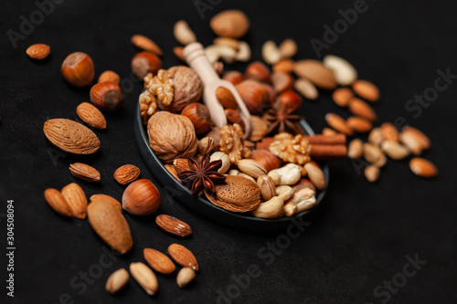 ifferent kinds on nuts and spices. Natural organic products for healthy lifestyle. Vegetarian food concept.  Raw almond, cachou, walnut, hazelnut, pistachio. Black background, closeup photo