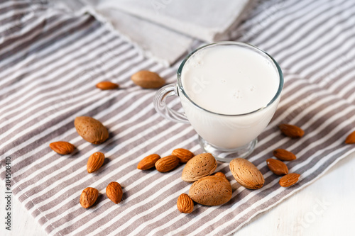 Fresh organic vegan almond milk. Alternative source of protein for vegetarians. Raw almonds  peeled and unpeeled to illustrate ingredients. Concept of healthy lifestyle. Closeup  white background.