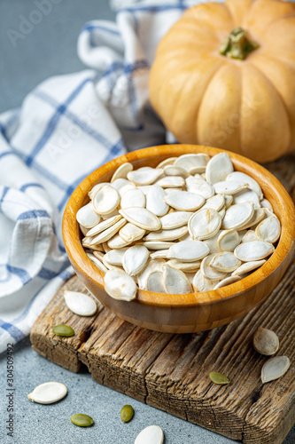 Unpeeled pumpkin seeds in a wooden bowl.