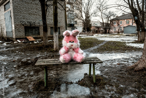 Wallpaper Mural pink plush rabbit sits on a bench in a poor residential area Torontodigital.ca