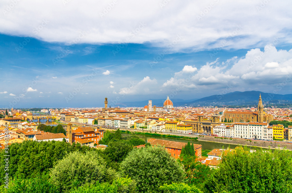 Top aerial panoramic view of Florence city with Duomo Santa Maria del Fiore cathedral, Ponte Vecchio bridge, buildings with orange red tiled roofs, Arno river, blue sky white clouds, Tuscany, Italy