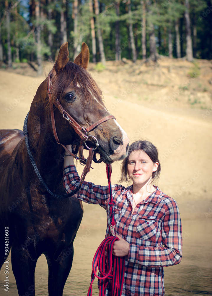 Obraz premium portrait of girl and red trakehner stallion horse in the river in the summer