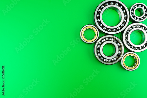 Ball bearing lying on a green background with copy space on the left side. Flat view from above.