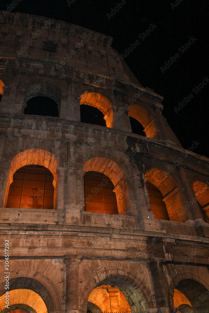 Colosseum in rome at night with illuminated arches 