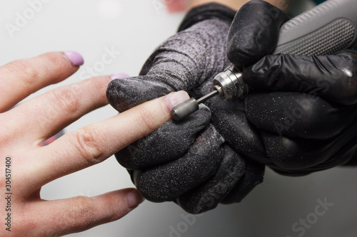 Manicure process. Close-up. Manicurist in black gloves. Gel Polish