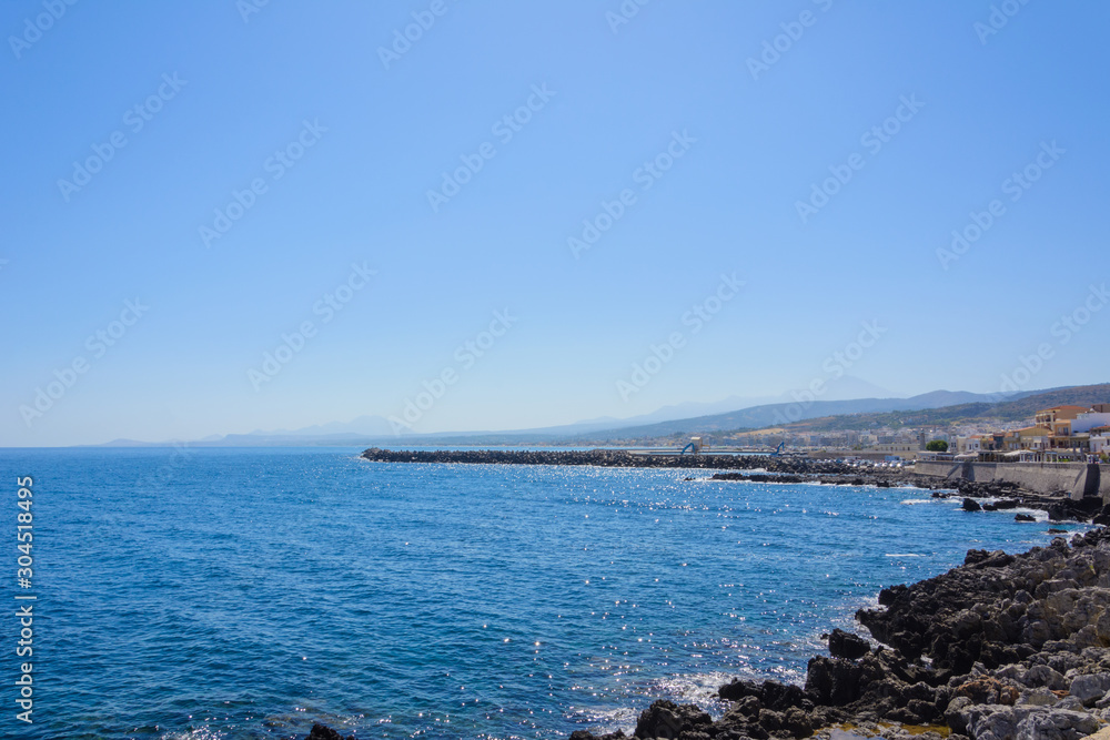 a small Bay with a breakwater built of stones. the city on the shore. silhouettes of mountains on the horizon.