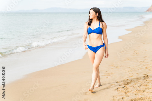 Happy Young Woman In Swimwear Walking On Beach