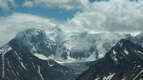 White snowy peaks of the mountain range under the clouds. The highest point of the Altai Mountains, Mount Belukha. 4k footage.