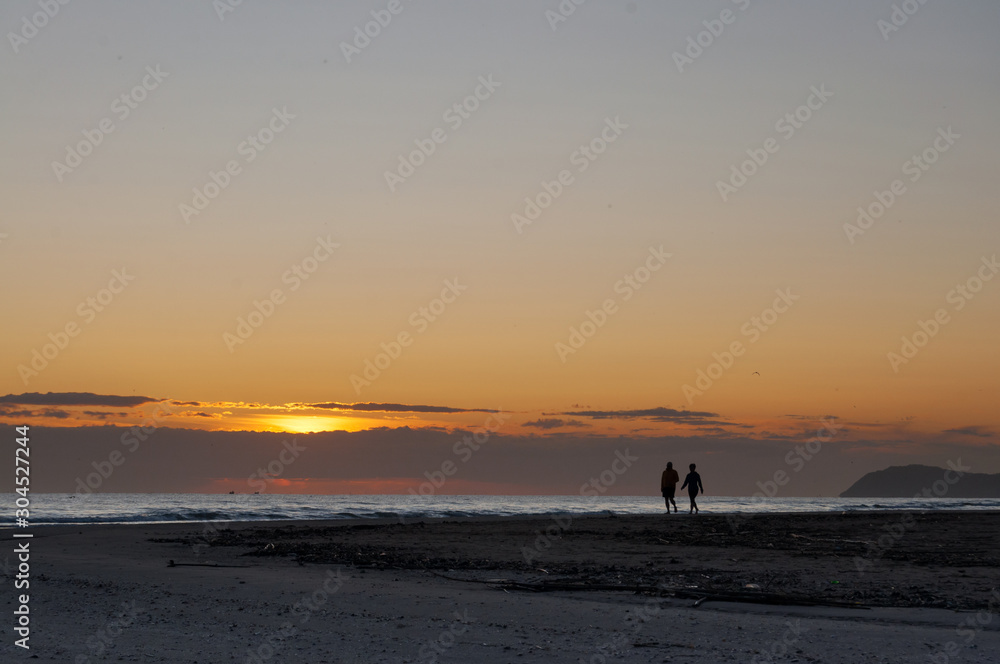 sunrise view and silhouette of couple walking on the beach