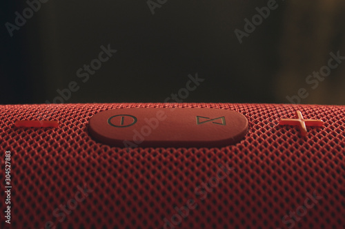 Wireless music speaker. Red Bluetooth speaker. Control and volume buttons. photo