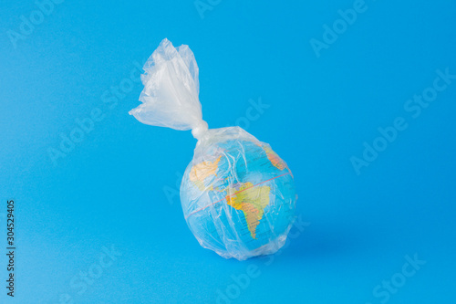 Planet earth inside a plastic bag over blue background.
