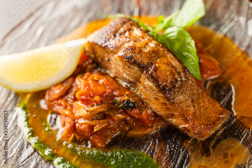 Close up of chum salmon marinated in lemon juice with stewed vegetables on wooden table
