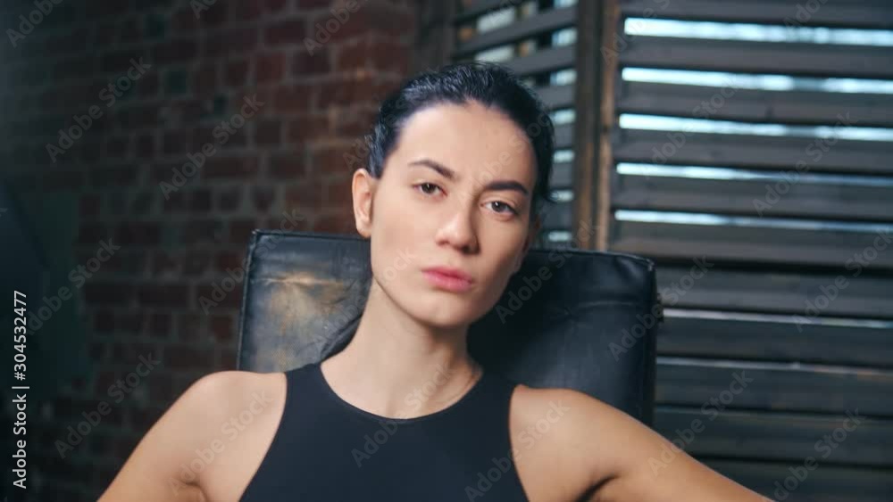Attractive face of mixed race young female mma fighter posing at boxing gym looking at camera Attractive face of mixed race young female mma fighter posing at boxing gym looking at camera