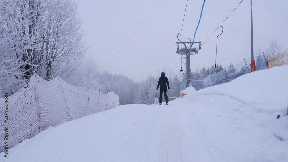 Ski resort during white winter season. Skier riding a ski lift type T-bar. Beautiful scenery covered with snow. Ski resort during white winter season. Skier riding a ski lift type T-bar. Beautiful scenery covered with snow.