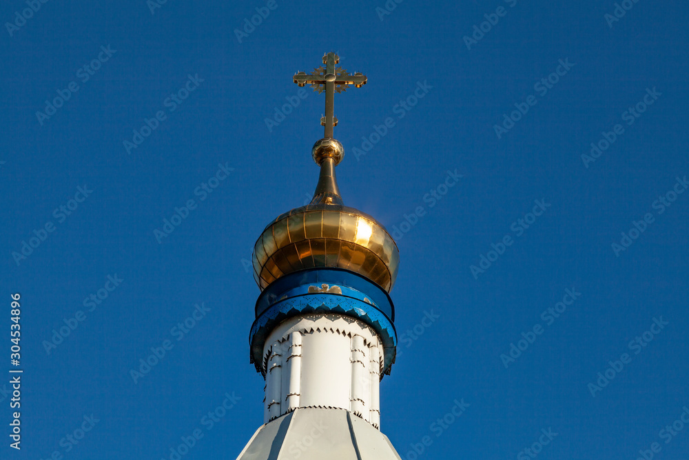 The dome of an Orthodox church with a cross on a background of blue sky. Dome and cross of gold color.