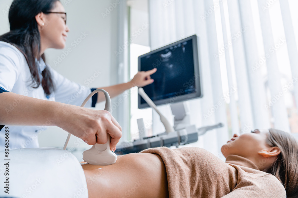 Mid adult female doctor using ultrasound scanner - obrazy, fototapety, plakaty 