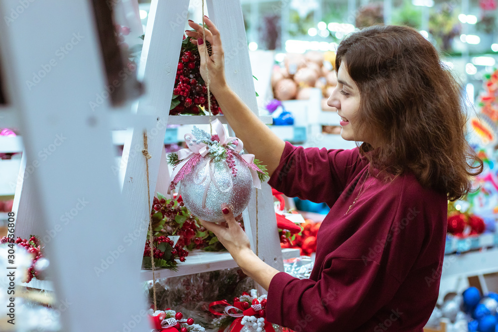 Obraz premium Young woman choosing toys at Christmas market. Winter holidays concept.