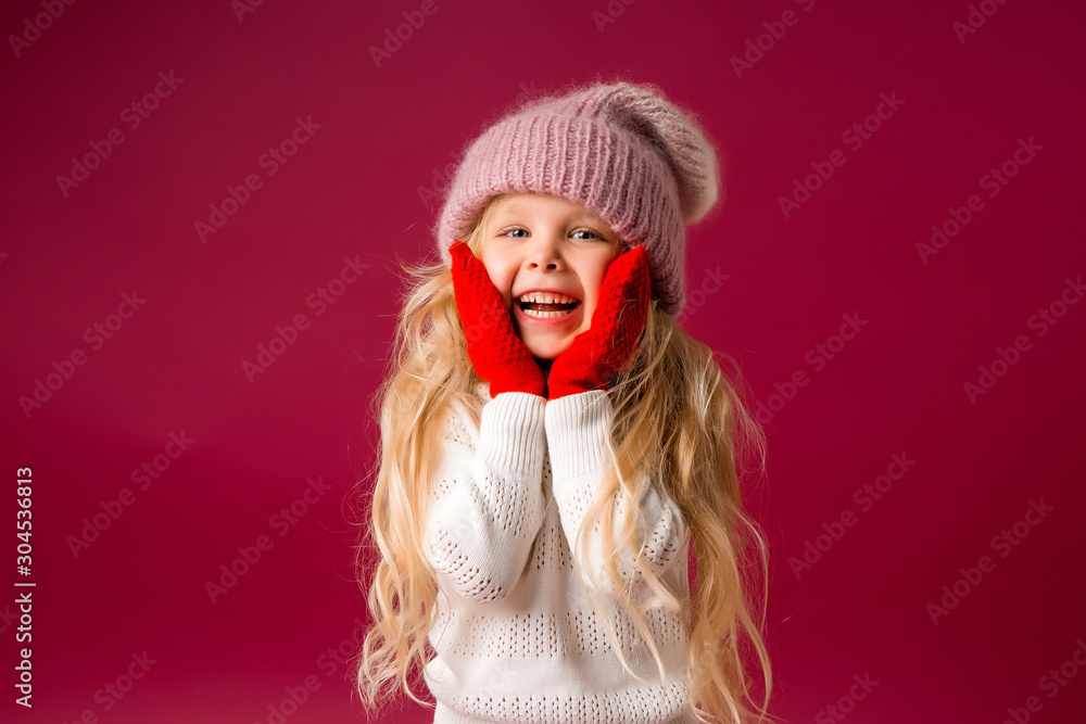 little blonde girl in a knitted hat and mittens smiles. winter clothes little blonde girl in a knitted hat and mittens smiles. winter clothes