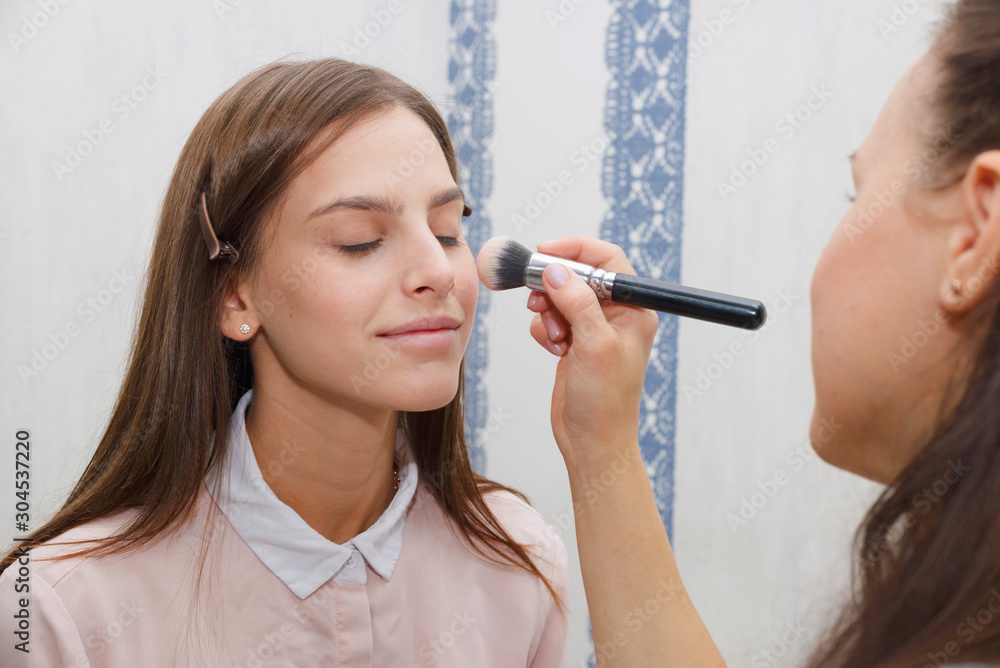 The process of creating makeup. Makeup artist working with a brush on the face of the model. The process of creating makeup. Makeup artist working with a brush on the face of the model.