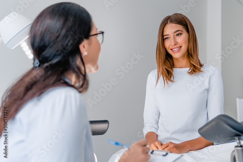 Gynecologist talking with young female patient during medical consultation in modern clinic photo