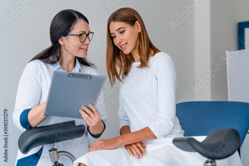 Adult smiling female gynecologist working with patient in modern clinic photo