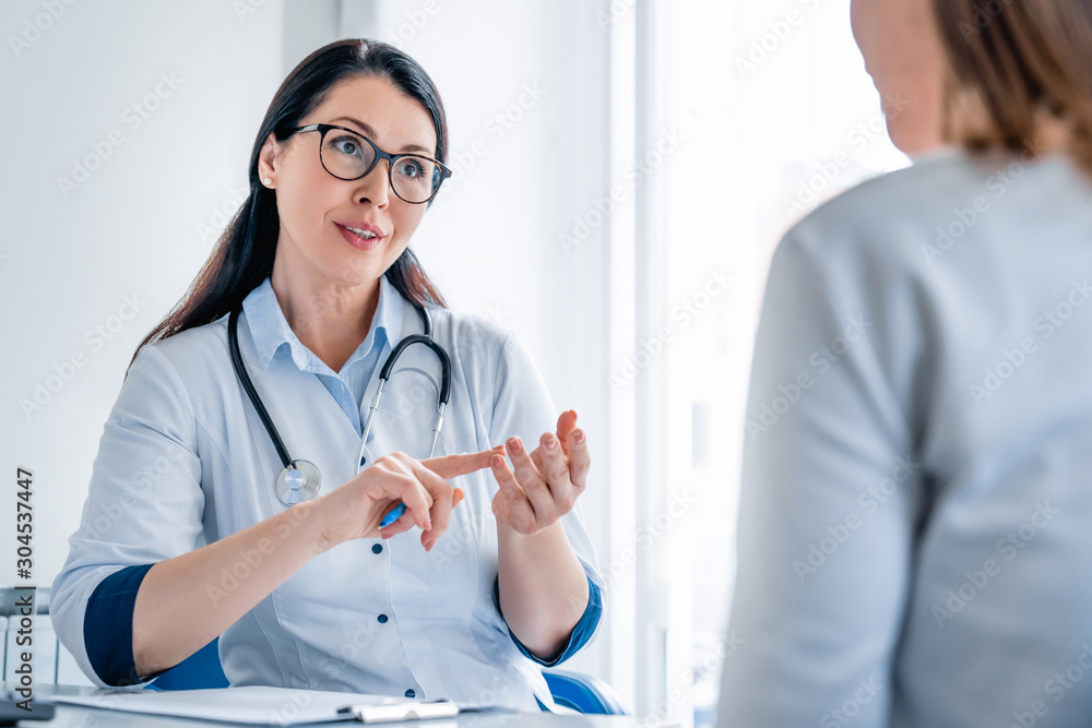 Smiling female doctor giving advice to female patient in cabinet Smiling female doctor giving advice to female patient in cabinet